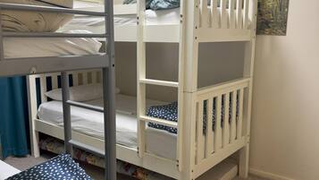 A bunk bed with a lower bunk and a top bunk, a small desk with a chair, and a painting on the wall.