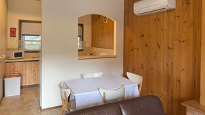 Un espace repas comprenant une table, des chaises et un appareil de climatisation fixé au mur.