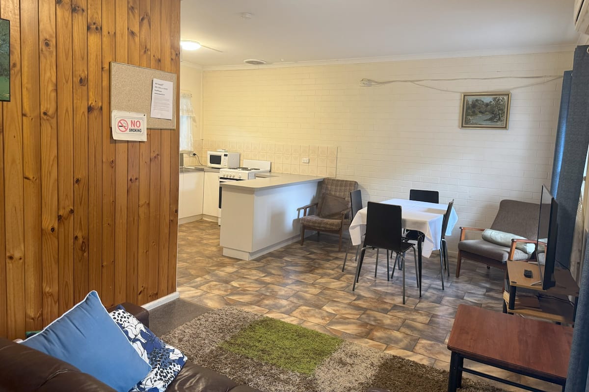 A compact living space with a kitchenette, a dining area, and a seating area with a couch and chairs.