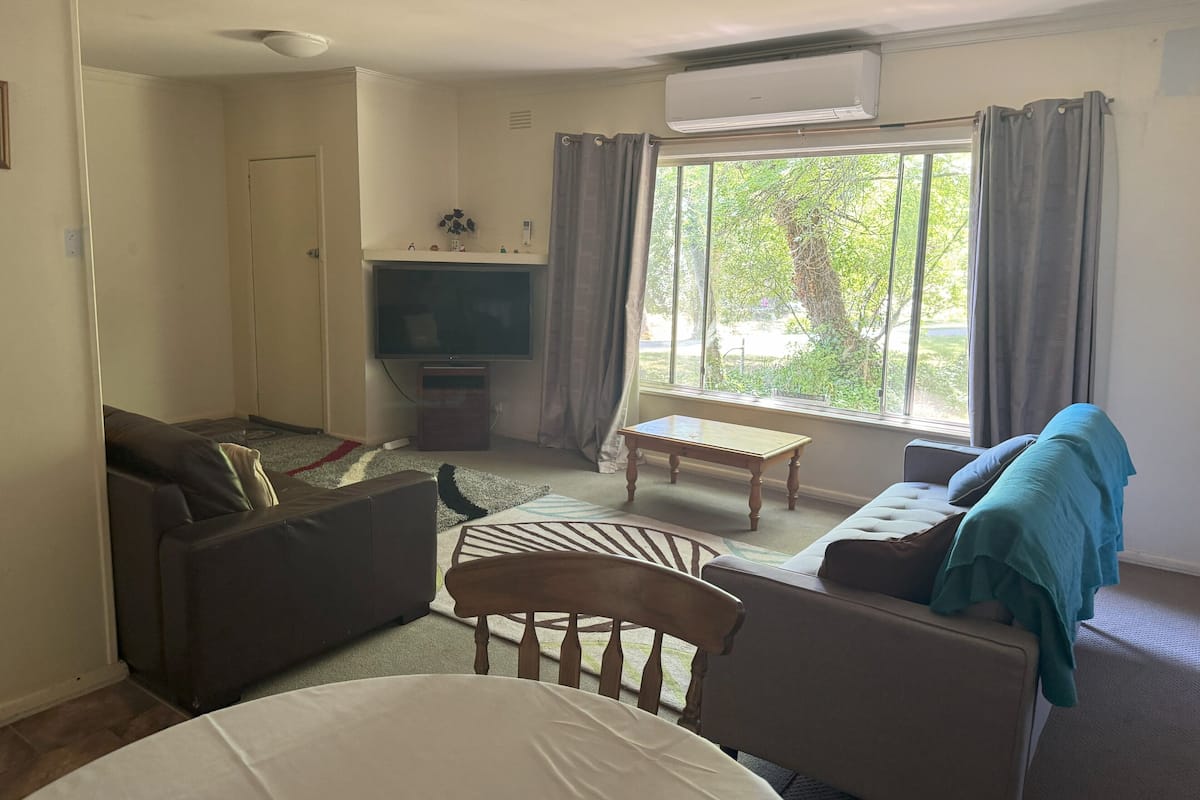 A living room with a sofa, a chair, a small table, and a TV.