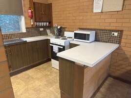 Una cocina con estufa, microondas y armarios.