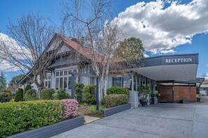 A modern building with a reception area, surrounded by well-maintained gardens and mature trees. - Cotswold Gardens (Armidale)