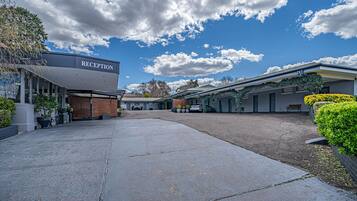 Zona de recepción con cielo despejado y nubes, un camino pavimentado y un edificio con un cartel que dice "RECEPTION".