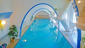 An indoor swimming pool with clear blue water, surrounded by white walls and blue arches. - Coral garden 7 pools (Yomitan)