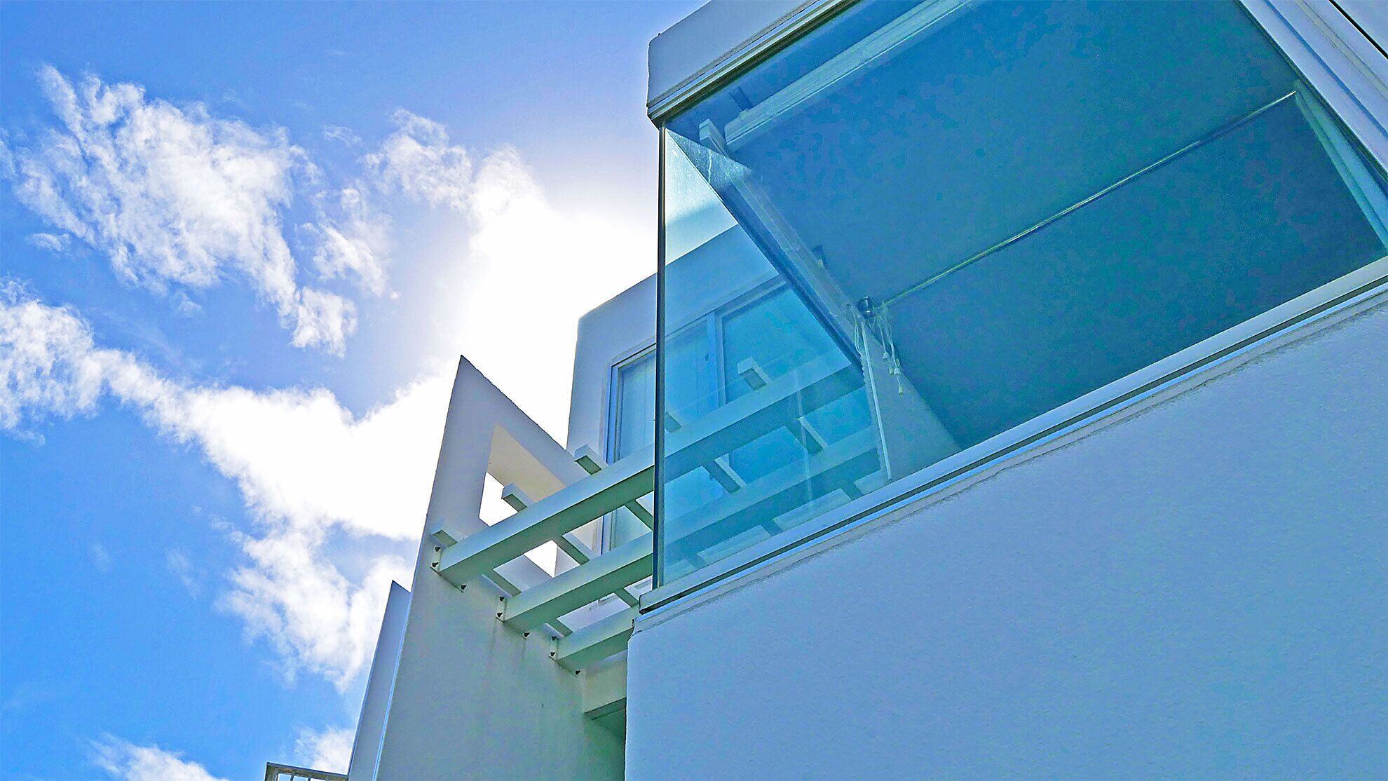 A building with a triangular architectural feature and a large window reflecting the sky and clouds.