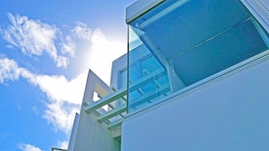 A building with a triangular architectural feature and a large window reflecting the sky and clouds.