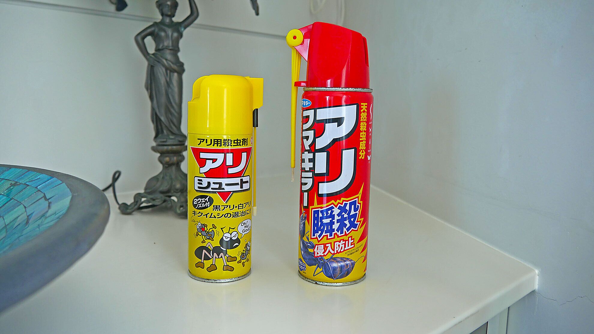 Two cans of insecticide on a white surface.