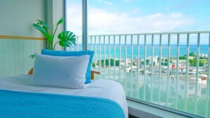 A hotel room with a bed, a view of the ocean, and a balcony with a railing. - Coral garden 7 pools (Yomitan)