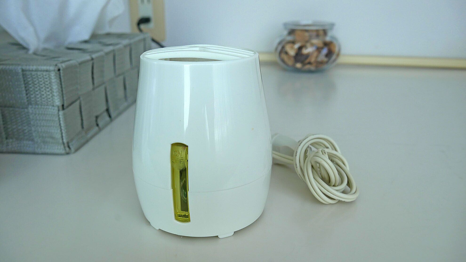 A white electric kettle with a power cord on a table.