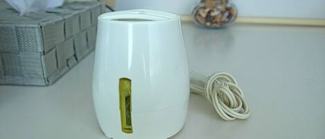 A white electric kettle with a power cord on a table.