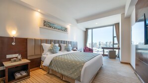 A modern hotel room with a large bed, a nightstand, a TV, and a city view. - L Hotel Changsheng (Zhuhai)