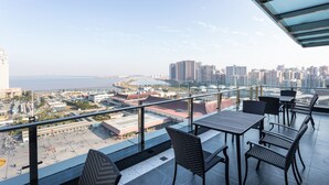 A balcony with a city view, outdoor seating, and a glass railing. - L Hotel Changsheng (Zhuhai)