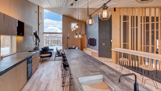 A modern kitchen with a long counter, wooden cabinets, and a built-in oven.
