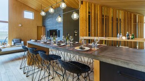 A modern kitchen with a wooden ceiling, bar stools, and a dining area set for a meal.