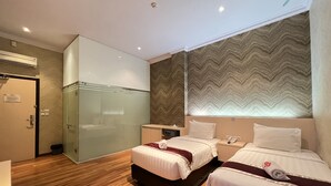 Ein Hotelzimmer mit zwei Betten, einer Dusche und einem Schminktisch mit Spiegel.