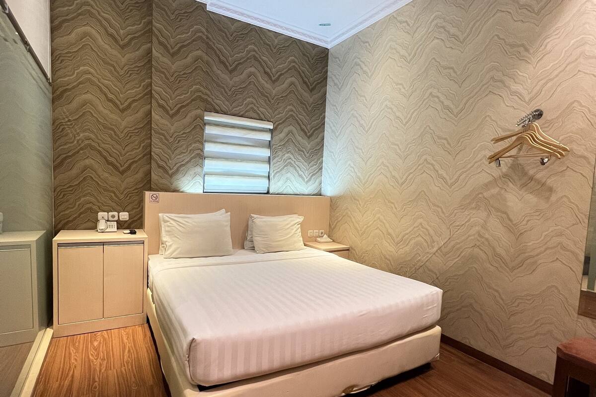Une chambre à coucher moderne avec un grand lit, un plancher en bois et un papier peint à motifs.