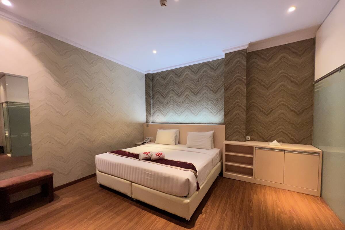 Une chambre à coucher moderne avec un grand lit, une table de chevet, une armoire intégrée et un miroir au mur.