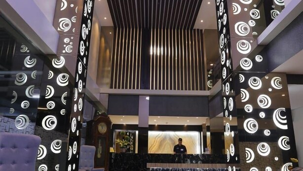 Eine moderne Lobby mit einer zentralen Rezeption, einem gemusterten Boden und einem außergewöhnlichen Deckenstil.