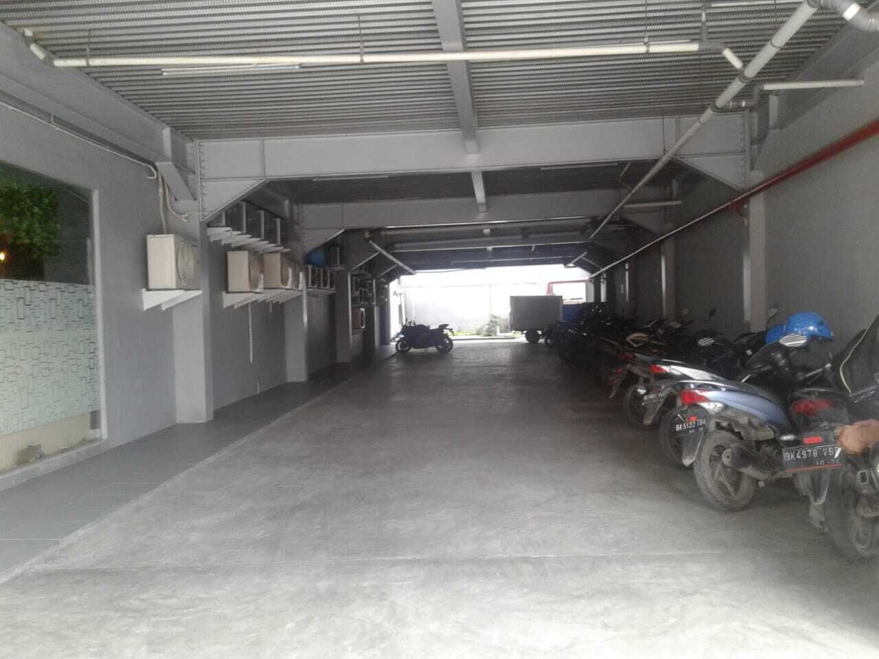 Área de estacionamento coberta com motocicletas estacionadas em ambos os lados.