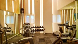 Ein Fitnessraum mit Cardiogeräten, Kurzhanteln und einem Spiegel.