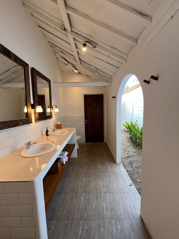 Un bagno con due lavabi, uno specchio grande e un mobile contenitore in legno.