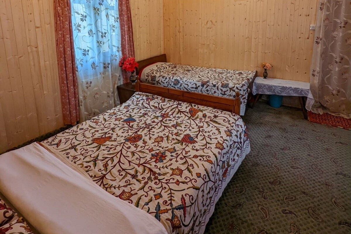 A room with two beds, wooden walls, a patterned ceiling, and a small picture on the wall.