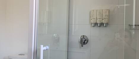 Un baño moderno con cabina de ducha de vidrio, un inodoro y un perchero para toallas.