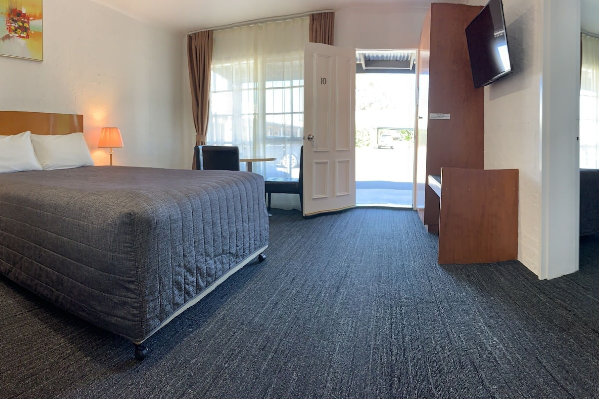A hotel room with two beds, a TV, and a view of the outside.