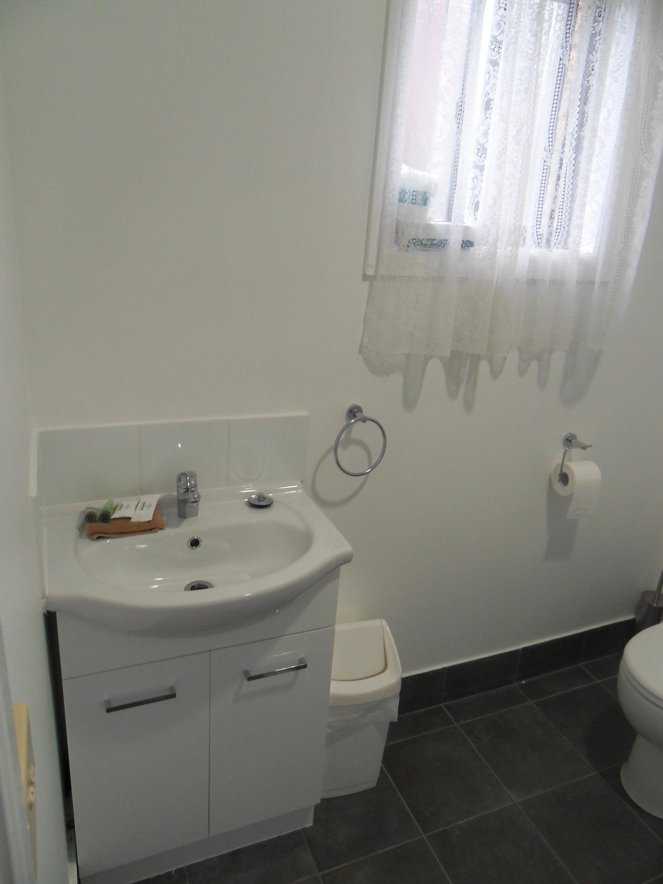 A bathroom with a white sink, toilet, and dark tiled floor.