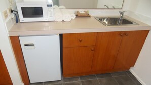A compact kitchen with a microwave, a sink, and a small refrigerator. - Swaggers Motor Inn (Yass)