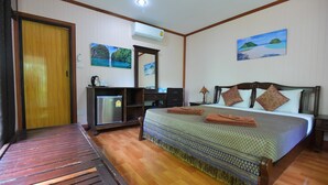 A bedroom with a bed, a desk, a chair, an air conditioner, and a door. - Anawin Bungalows (Krabi)