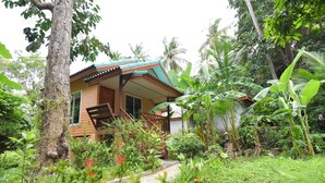 A house with a porch, surrounded by lush greenery and a banana plant. - Anawin Bungalows (Krabi)