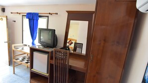 A compact room with a wooden desk, a television, a mirror, and a blue curtain. - Anawin Bungalows (Krabi)