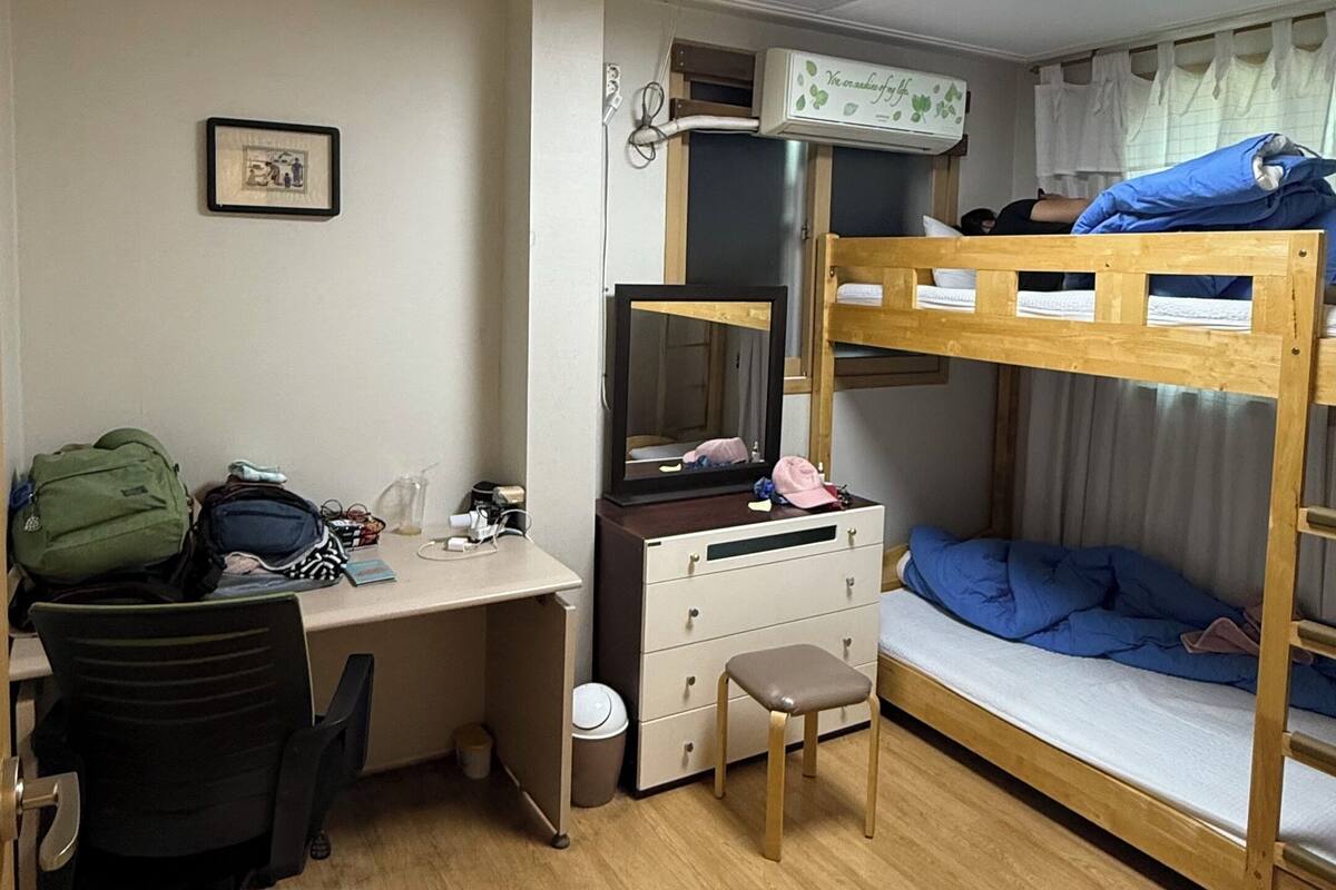 Une chambre de dortoir équipée d’un bureau, d’une chaise, de lits superposés et d’une commode.