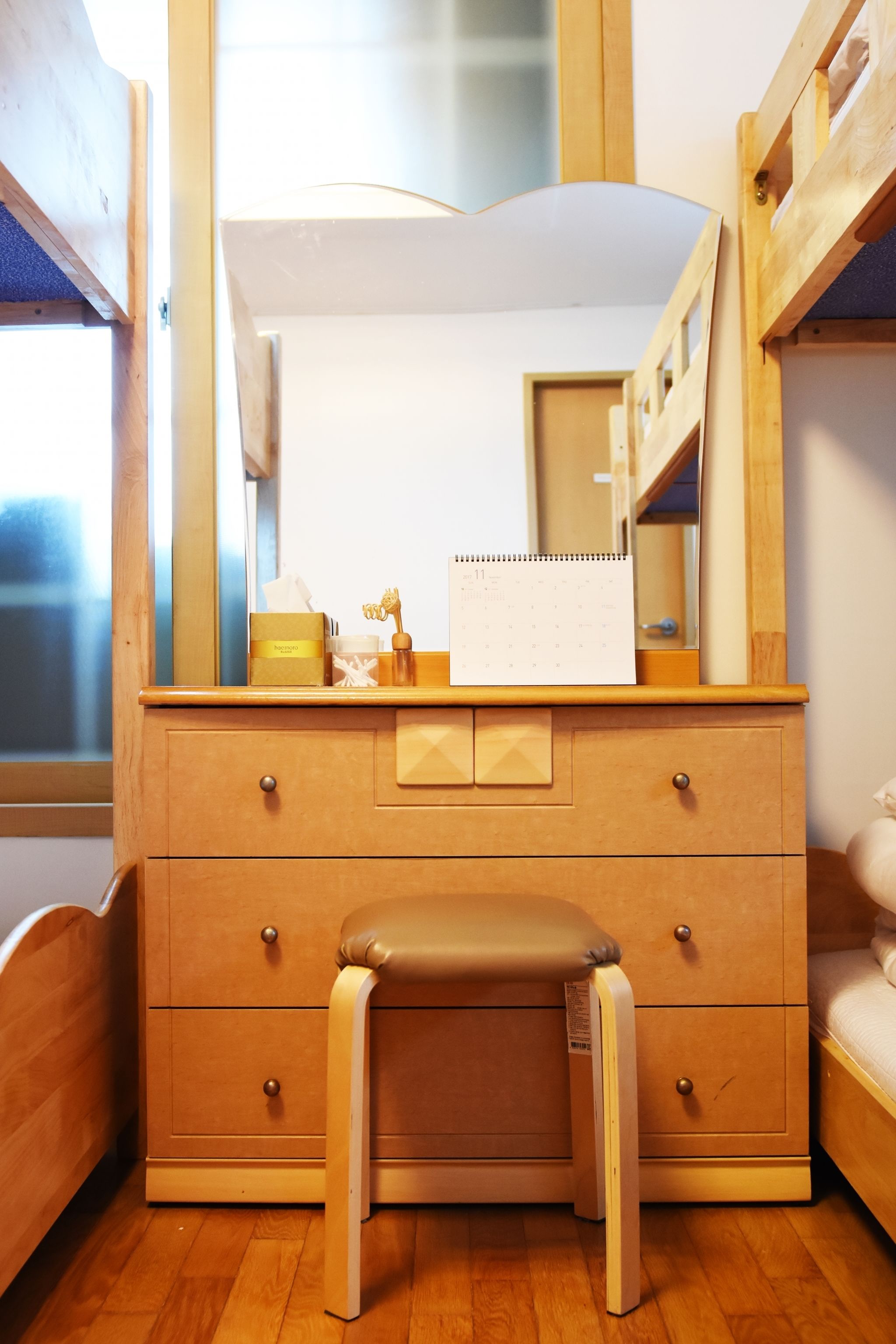 A wooden dresser with a mirror, a small stool, and a calendar.