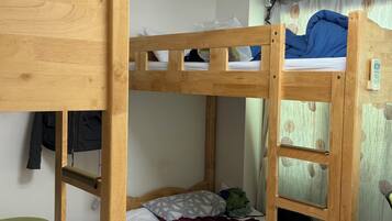 A bunk bed room with a wooden headboard, a green stool, and a ceiling fan.