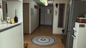 Une cuisine moderne avec des meubles blancs, un réfrigérateur et un luminaire suspendu original.