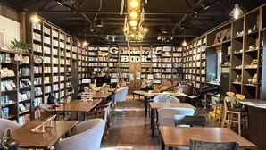 Un café-librairie chaleureux, avec des tables en bois, des fauteuils confortables et des étagères remplies de livres.