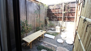 A small outdoor garden area with a wooden bench, stepping stones, and a bamboo fence. - JQ Villa Kyoto Maiko Han-Inn (Kyoto)
