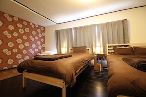 A bedroom with two beds, a wooden headboard, a nightstand, and a wall with a floral pattern.
