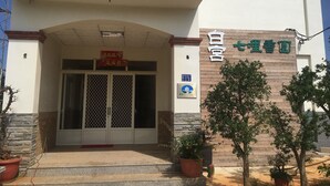 A building entrance with a sign reading "White House" and a wooden panel with Chinese characters. There are potted plants and a clear sky. - White House (Jinning)