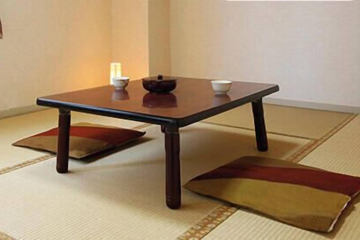 A tatami mat room with a low table, cushions, and a small table with a candle.