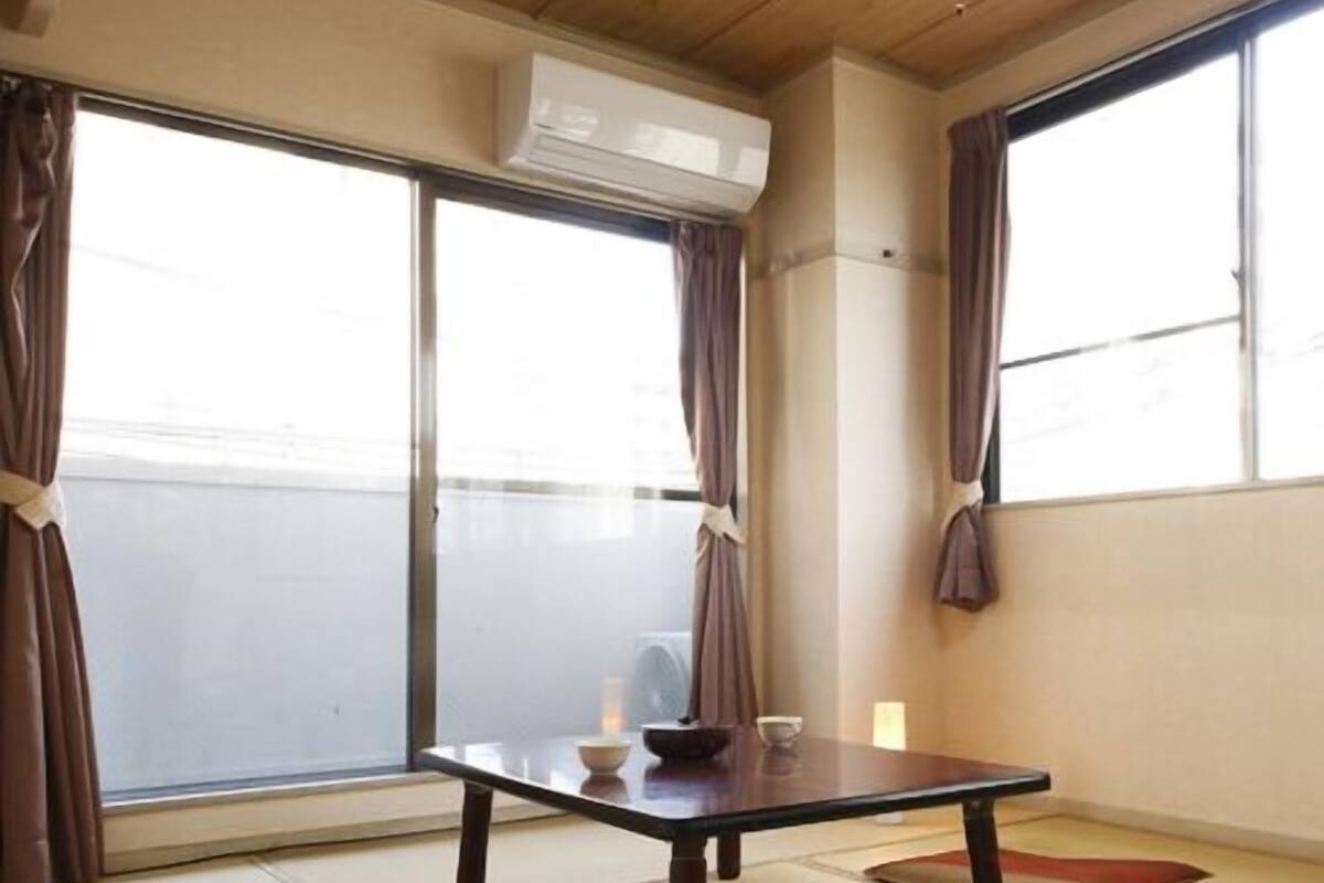 A room with tatami flooring, a low table, and a sliding door.