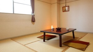 A traditional Japanese room with tatami flooring, a low table with a tea set, and a hanging picture frame. - Kyomai Inn (Kyoto)