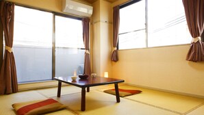 A room with tatami mat flooring, a low table with a bowl and a cup, and a sliding door with a view of a building outside. - Kyomai Inn (Kyoto)