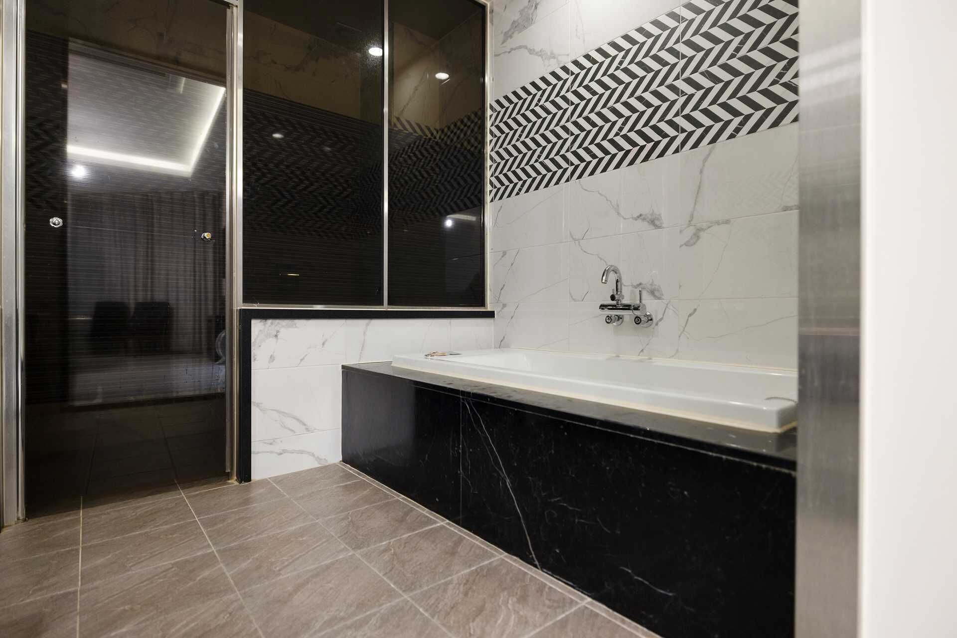 A modern bathroom with a large mirror, a sink, and a shower area.