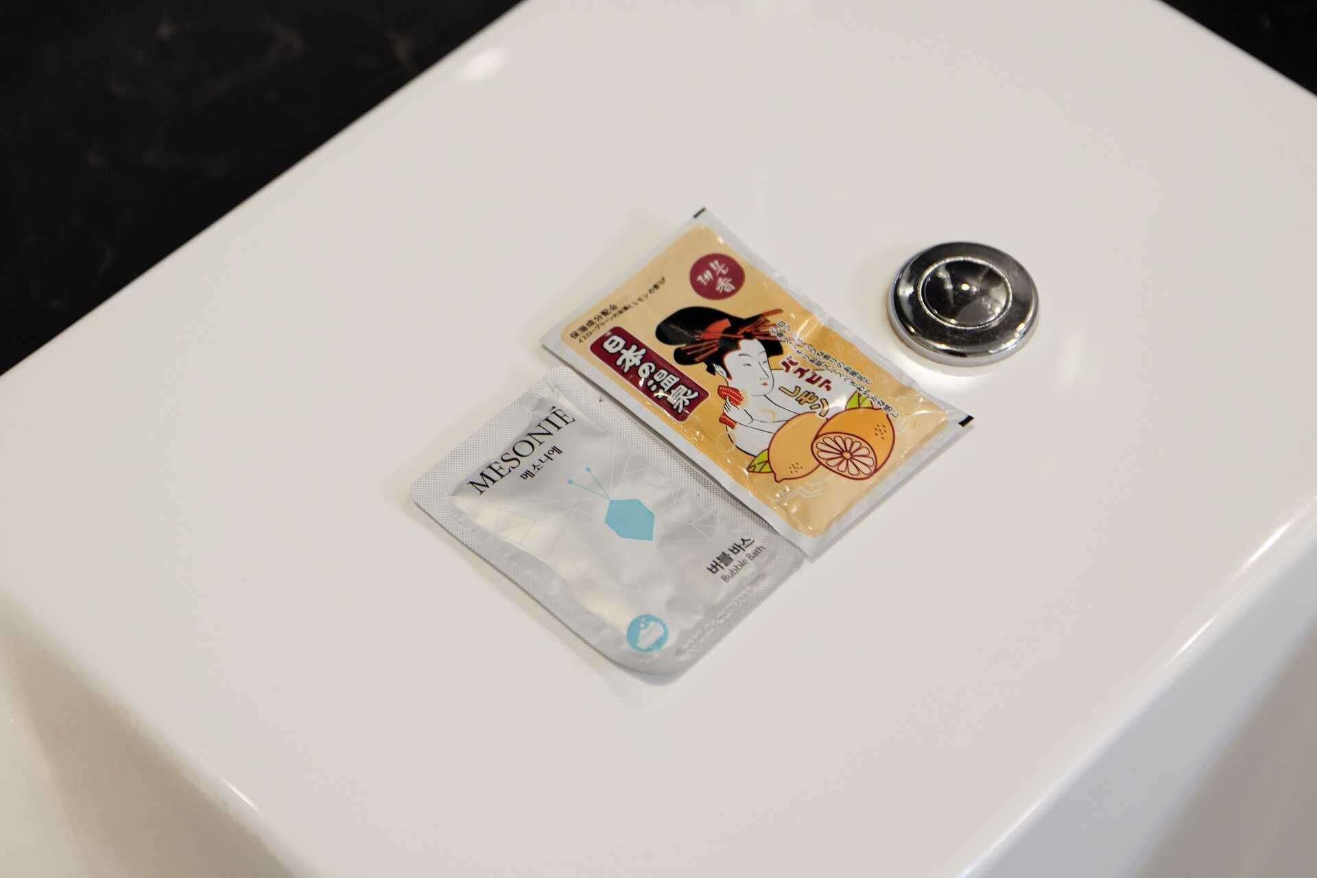 Ein Waschbecken mit zwei Packungen Badeschaum und einem Metall-Ablauf.