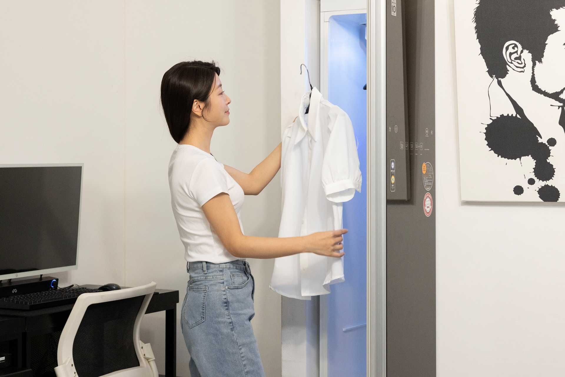 A person hanging a white shirt on a door.