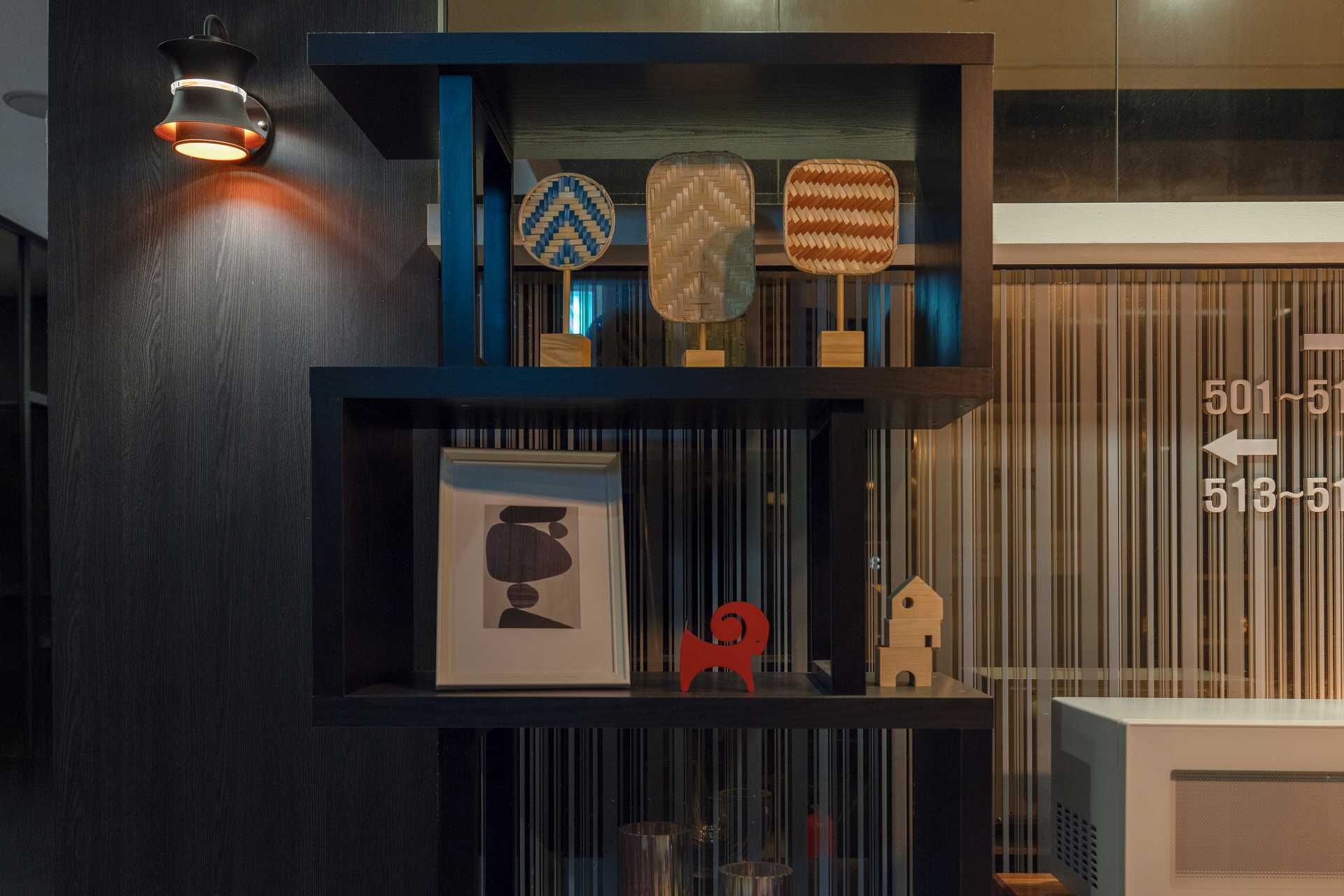 Una estantería de madera oscura con objetos decorativos, como un cuadro enmarco, una escultura roja y tres cestas tejidas.