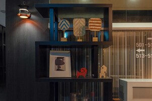 Una estantería de madera oscura con objetos decorativos, como un cuadro enmarco, una escultura roja y tres cestas tejidas.